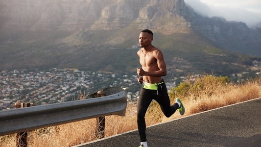 male runner muscular torso running on asphalt with a blurry mountain and landscape in the background