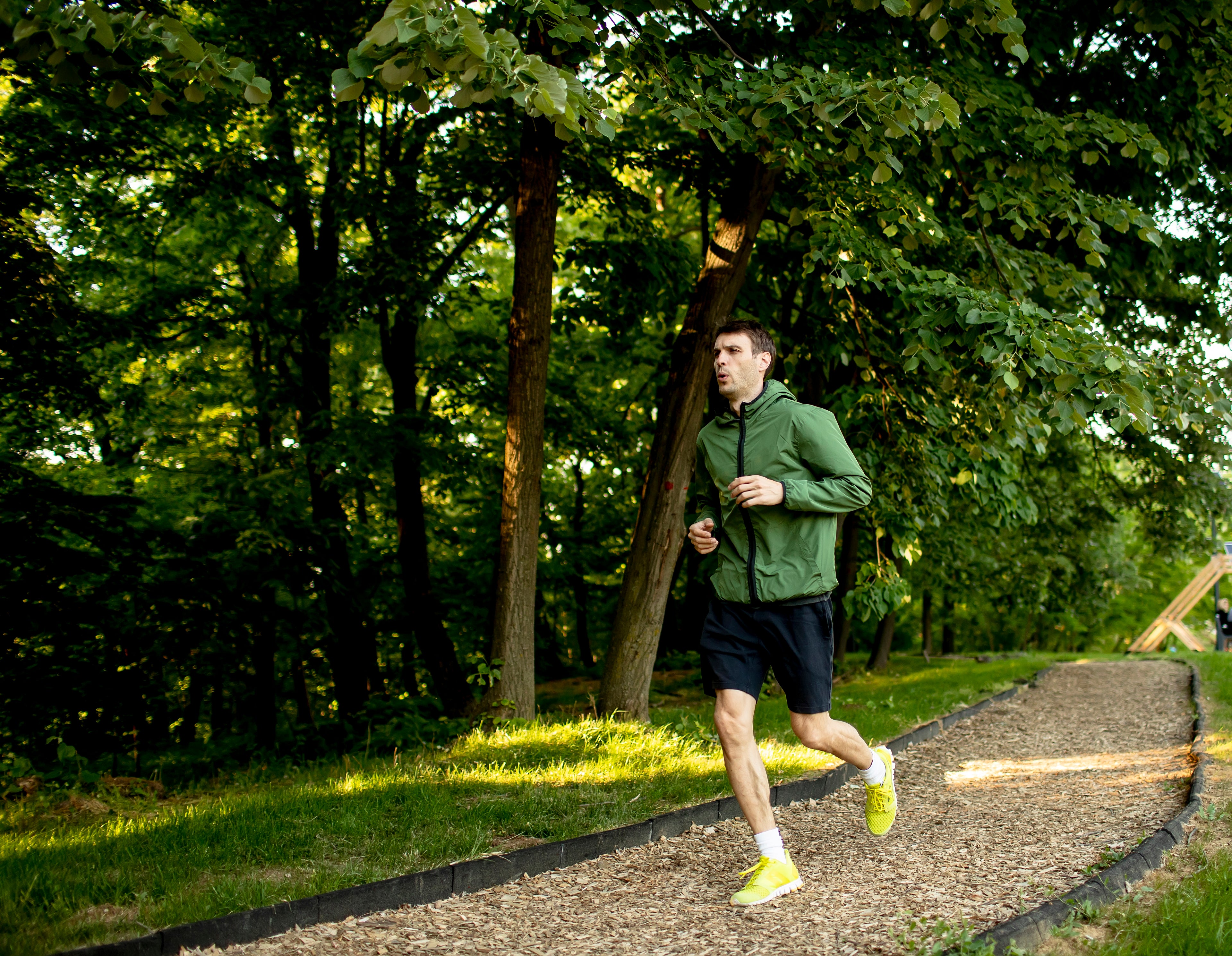 Man running on a path in a park with trees in the background