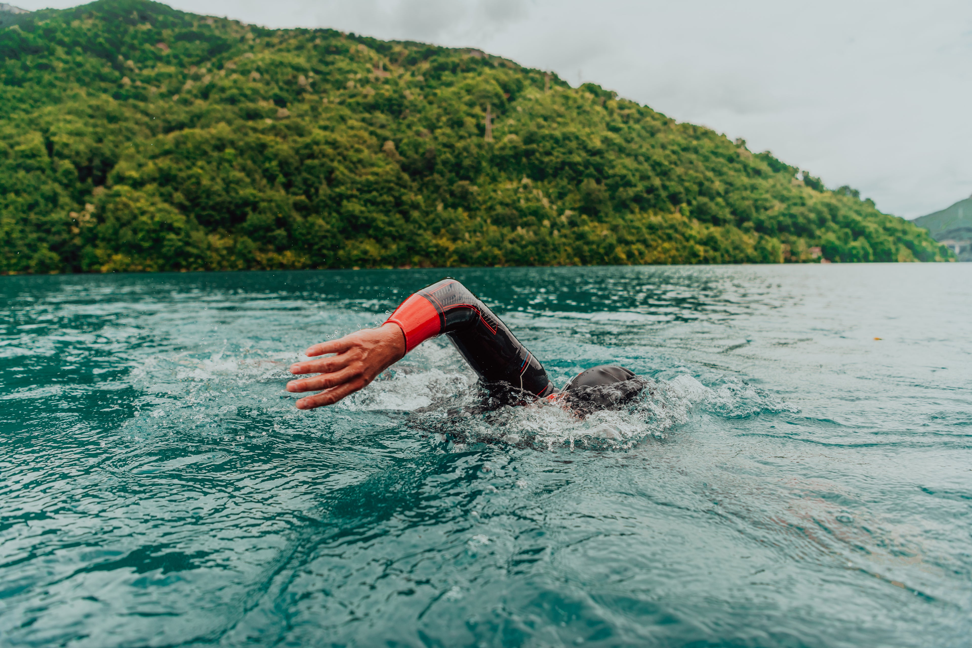 Person swimming in a lake with a mountainous background